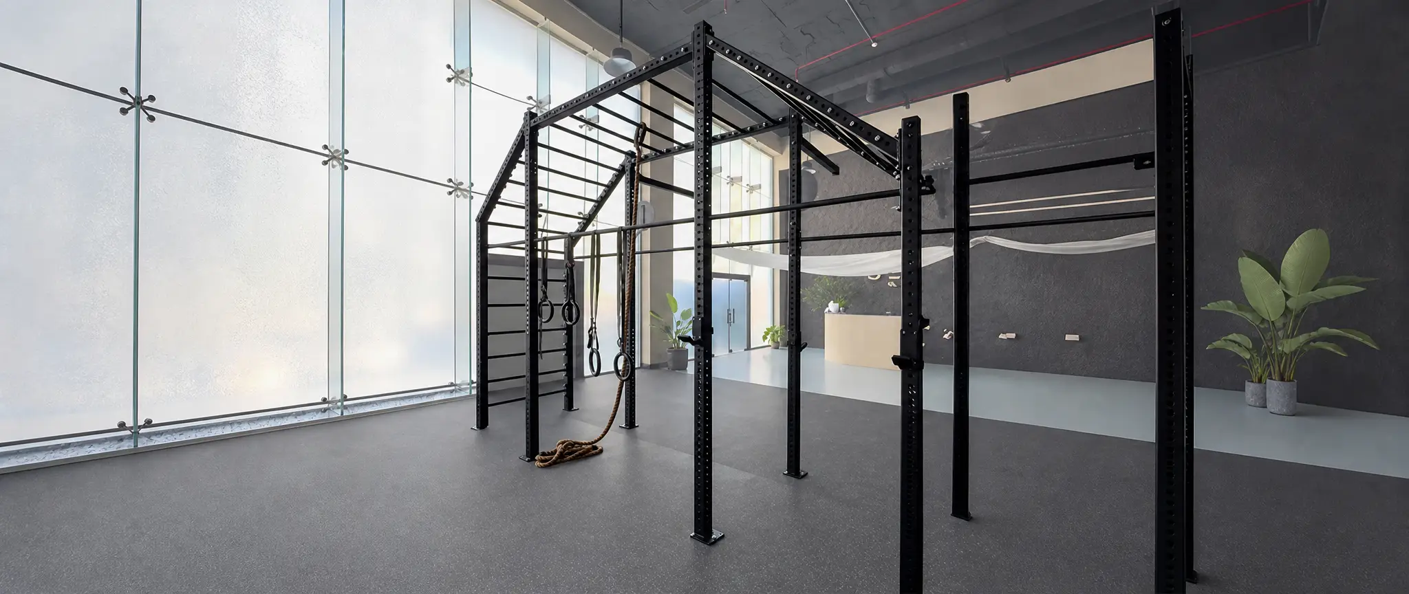 A dual-cable functional trainer in a dim training hall, single overhead light.